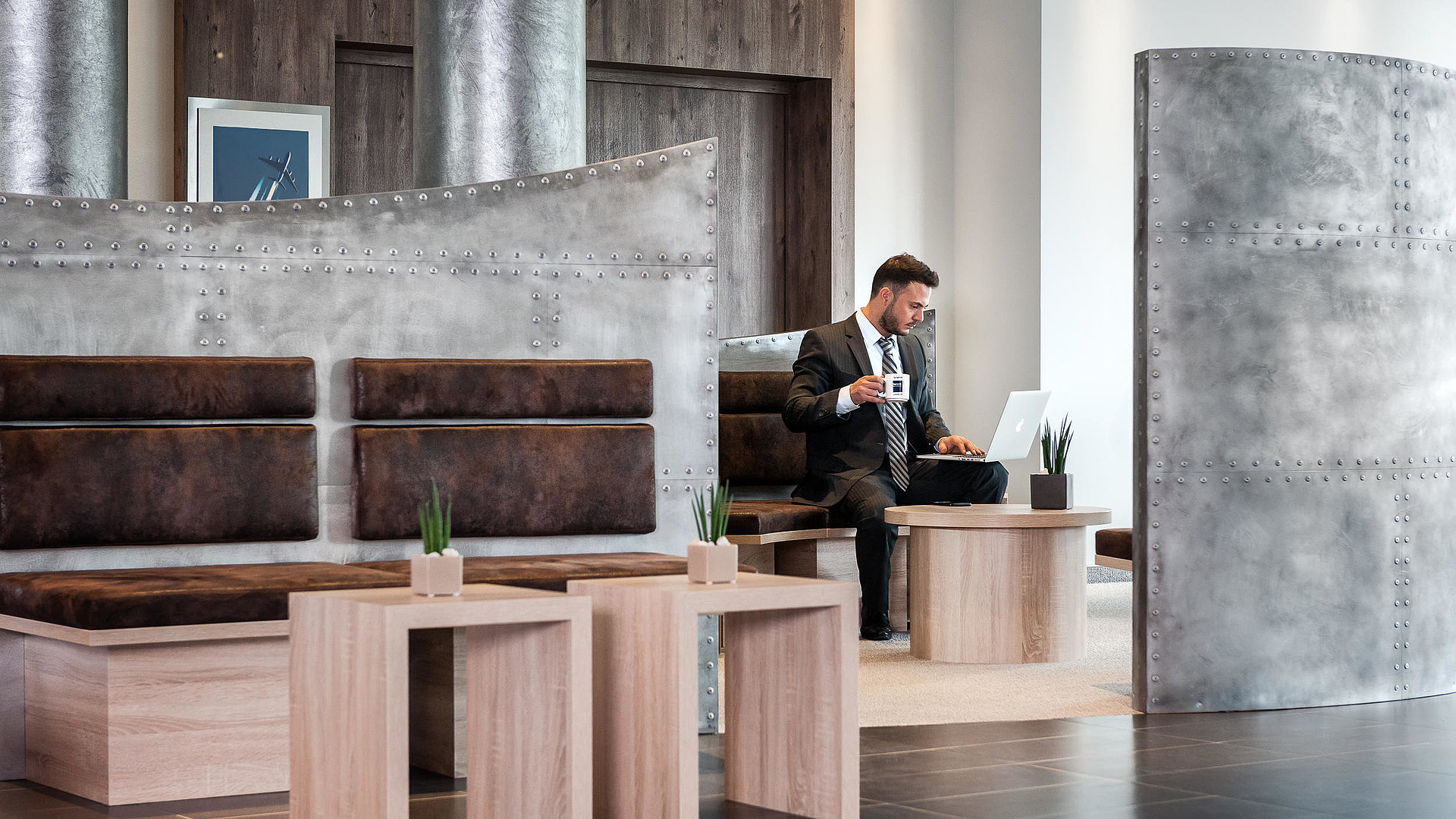 Mann mit Notebook und Kaffee in der Lobby des Hotel Essential by Dorint Stuttgart-Airport